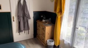 ein Schlafzimmer mit einer Holzkommode und einem Fenster in der Unterkunft Maple Tree Chambre d'hôtes in Darnac