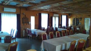 a dining room with tables and chairs and windows at Lovac in Štrpce