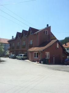 ein großes rotes Gebäude mit Autos auf einem Parkplatz in der Unterkunft Lovac in Štrpce