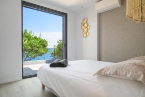 Saint-AntoineにあるProche Monaco, vue mer, accès plage et jardin privatifのベッドと大きな窓のある寝室