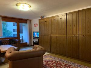 sala de estar con armarios de madera, sofá y TV en Hilburgs-Domizil, en Zermatt