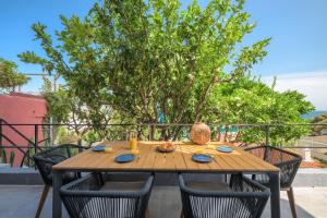 une table en bois entourée de chaises sur la terrasse. dans l'établissement Proche Monaco, vue mer, accès plage et jardin privatif, à Saint-Antoine