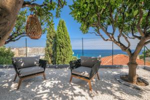 Saint-AntoineにあるProche Monaco, vue mer, accès plage et jardin privatifの海の横の木の下に座る椅子2脚