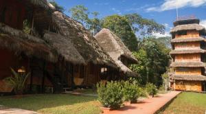 a group of buildings with grass roofs and a tower at Caiman Lodge in Cuyavenus
