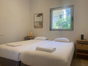 two beds in a room with a window at Relax Sea View 3BR in Gordon Beach by Holyguest in Tel Aviv