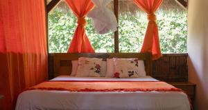 Schlafzimmer mit einem Bett mit roten Vorhängen und einem Fenster in der Unterkunft Caiman Lodge in Cuyabeno