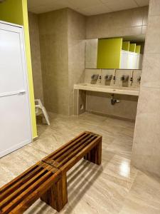 baño con banco de madera en una habitación en Hostel Tropico 20 PDC, en Playa del Carmen