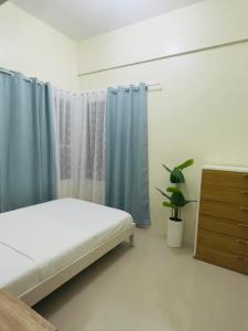 1 dormitorio con 1 cama, cortinas azules y una planta en ONE PAVILLION PLACE, en Cebú