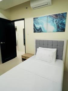 Un dormitorio con una cama blanca y una pintura en la pared en ONE PAVILLION PLACE, en Cebú