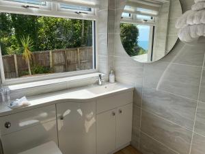 ein Bad mit einem Waschbecken und einem Spiegel in der Unterkunft Conifers in Lyme Regis