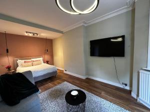 a bedroom with a bed and a flat screen tv at Spacious Studio for 4 flat near Regents Park n2 in London