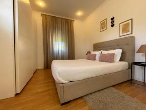 1 dormitorio con 1 cama grande con sábanas y almohadas blancas en Burgães II Apartment, en Oporto