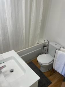 a white bathroom with a toilet and a sink at Burgães II Apartment in Porto