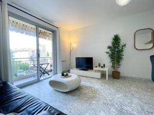 a white living room with a couch and a tv at Cosy deux pièces in Menton