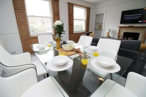 comedor con mesa de cristal y sillas blancas en Spacious Georgian 3bedroom Apartment, 5 mins from Bath Abbey, en Bath