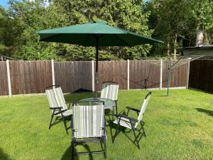 a table and chairs with a green umbrella in a yard at The Annexe at Gomo in East Winch