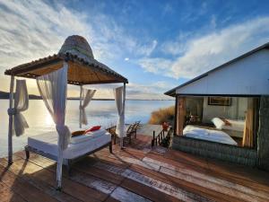 a deck with a bed and a gazebo on the water at Casitas del Titicaca Peru in Puno