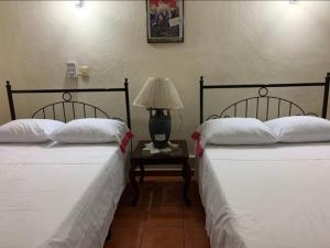 two beds in a room with a table with a lamp at Hotel Jacaranda in Tuxtla Gutiérrez