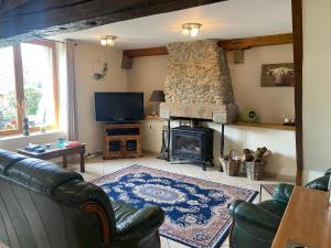 - un salon avec un canapé et une cheminée dans l'établissement The Gingerbread House Cottage, à Beauficel