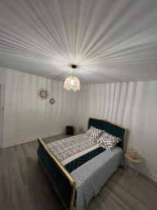 een slaapkamer met een bed en een kroonluchter bij Gîte le clos in Saint-Sulpice-de-Faleyrens