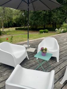 dos sillas blancas y una mesa y una sombrilla en Chambre de la cime des pins, en Crévin