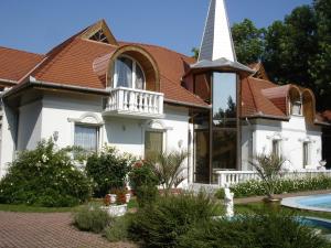 a church with a white steeple and a house at Kings Pension in Gyenesdiás