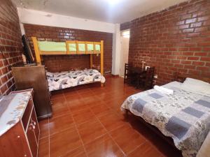 a room with two beds and a brick wall at 1 habitación - 4 huéspedes in Oxapampa