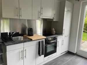 una cocina con armarios blancos y fregadero en 2-Zimmer Ferienwohnung an ruhiger Lage, en Triesenberg