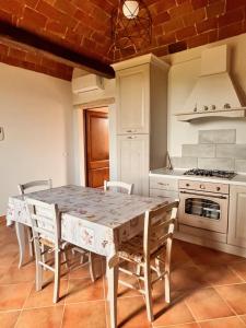 una cucina con tavolo, sedie e piano cottura di Le volte in Toscana a Bettolle