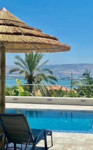 uma vista para uma piscina com uma cadeira e um guarda-sol em Kinneret View em Kinneret