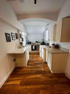 a large kitchen with white cabinets and wooden floors at Spacious studio for 4 near Regents Park n1 in London