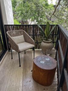 a chair and a table with wine glasses on a balcony at Ophelia Tulum Condo Hotel in Aldea Zama in Tulum