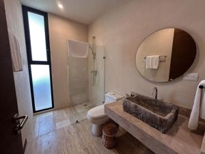 a bathroom with a sink and a toilet and a mirror at Ophelia Tulum Condo Hotel in Aldea Zama in Tulum