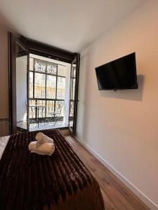 a bedroom with a bed with a flat screen tv on the wall at Hostal Arenal Madrid in Madrid