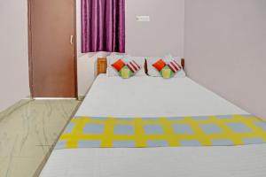 a bedroom with a large white bed with colorful pillows at Super OYO Hotel Happy Inn in Patna