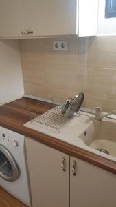 a kitchen counter with a sink and a washing machine at Casă privată in Rozavlea +9 photos