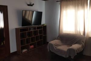 a living room with a tv and a chair and a window at Casă privată in Rozavlea