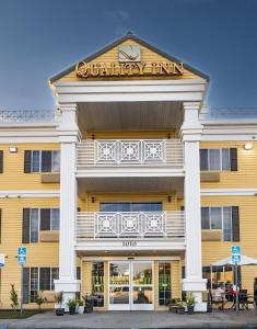 un bâtiment jaune avec un panneau indiquant une auberge de vacances dans l'établissement Quality Inn & Suites, à Tulare
