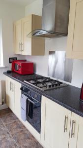 a kitchen with a stove and a red microwave at Comfortable Family Home in Immingham in Immingham