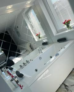 a white bathroom with a tub and a window at Apartamenty Modrzewiowa Zator in Piotrowice