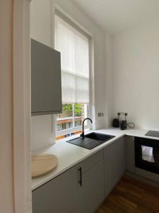 eine weiße Küche mit einem Waschbecken und einem Fenster in der Unterkunft Stylish Studio for 2 near Regents Park n4 in London