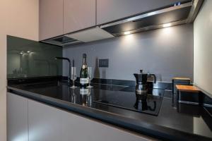 a kitchen with a black counter top with a bottle of wine at Officine Cavour - Appartamenti la Quercia in Padova