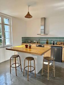 een keuken met een houten eiland met drie barkrukken bij Appartement Montpellier centre in Montpellier