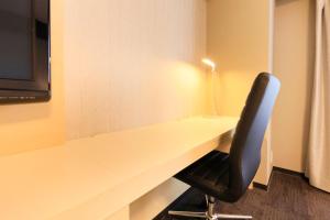 escritorio en una habitación con silla y lámpara en Richmond Hotel Narita en Narita