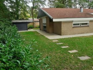 a house with a garage and a grass yard at Bungalow/vakantiehuis op park Bavelds Dennen in Denekamp