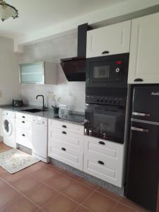 una cocina con armarios blancos y un aparato negro en Casa Concha, en Porto do Son
