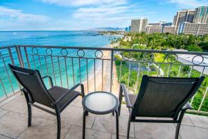 duas cadeiras e uma mesa numa varanda com o oceano em Waikiki Shore by OUTRIGGER - Select Your Unit em Honolulu