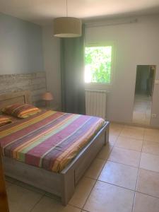 ein Schlafzimmer mit einem Bett in einem Zimmer mit einem Fenster in der Unterkunft Les jonquiers, gîte indépendant cosy avec jardin in Aubagne
