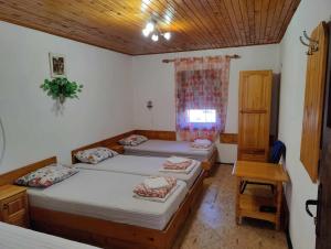 a bedroom with two beds and a table and a window at Стаи за гости Кичка in Shkorpilovtsi