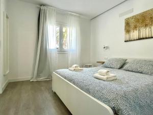 een witte slaapkamer met een bed met handdoeken erop bij En el Casco Histórico in La Laguna